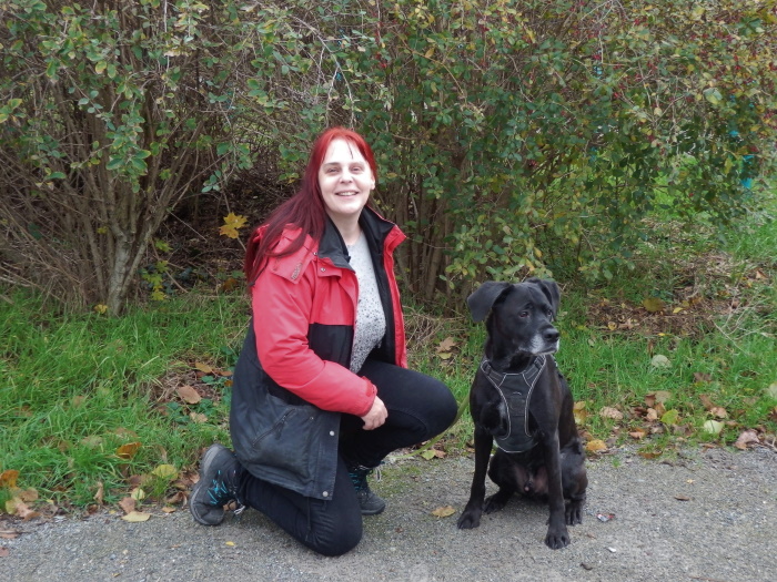 Iris Berger auf einem Weg in der grünen Lobau kniend mit ihrem Hund Bounty